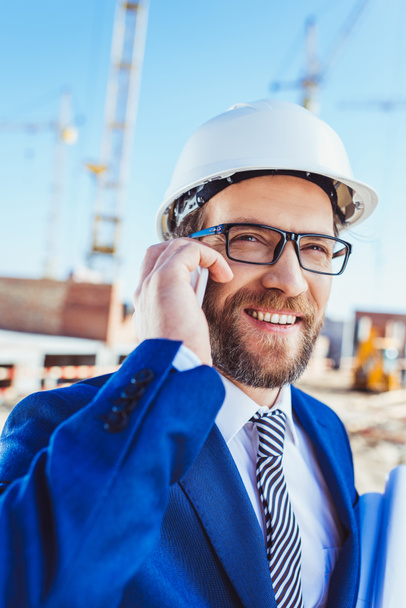 Businessman talking on phone at construction site - 写真・画像