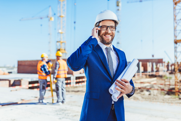 Businessman talking on phone at construction site - Photo, Image