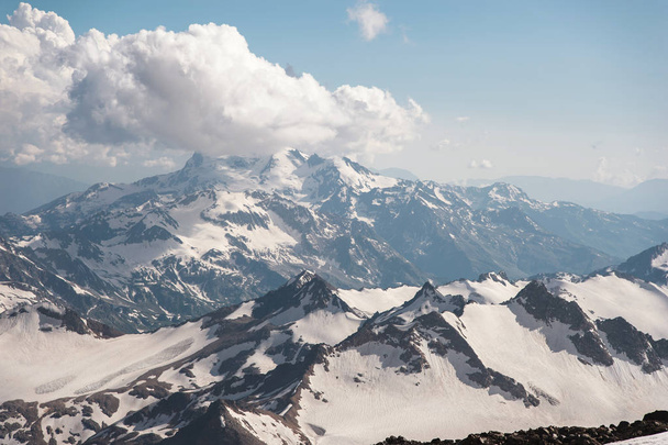 Cielo blu scuro con nuvole sulle cime rocciose delle montagne ricoperte di ghiacciai e neve
 - Foto, immagini