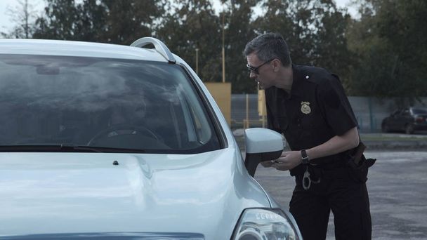 Офицер полиции останавливает водителя автомобиля
 - Фото, изображение