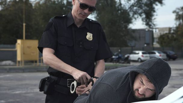 Policeman arresting criminal on parking lot - Фото, зображення