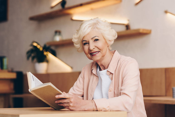 senior woman with book in cafe - Фото, зображення