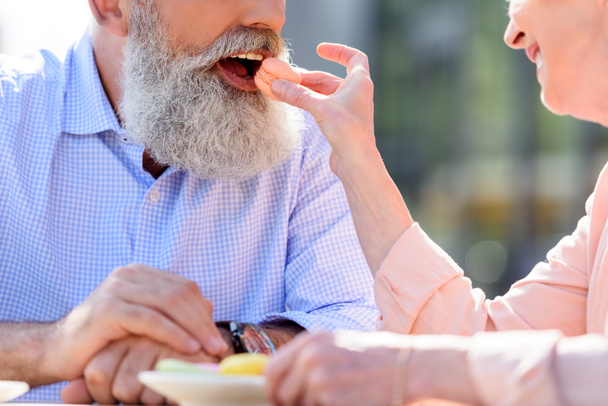 woman feeding husband with macaroon  - Zdjęcie, obraz