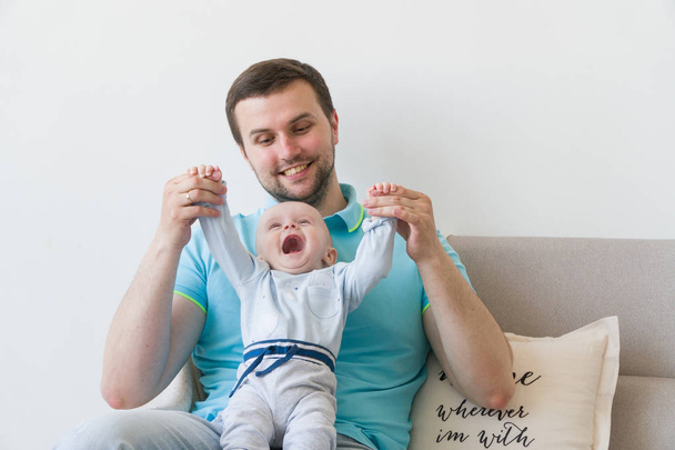 Close-up portrait of happy young father hugging and kissing his sweet adorable child. Indoors shot, concept image - Valokuva, kuva