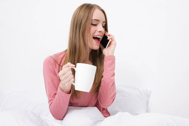 woman with coffee talking on smartphone - Фото, изображение