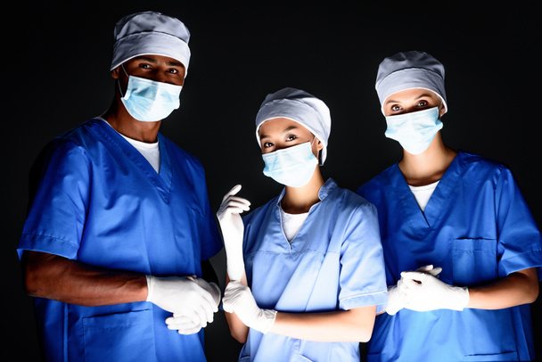 cirujanos multiétnicos con máscaras médicas
 - Foto, Imagen