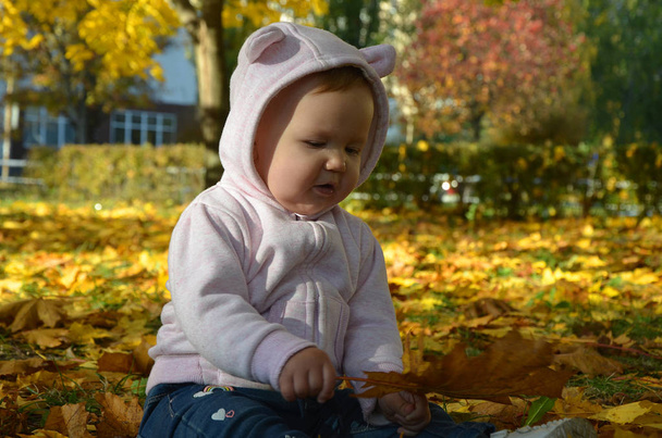 entzückendes glückliches Mädchen, das die umgefallenen Blätter aufwirft und im Herbstpark spielt - Foto, Bild