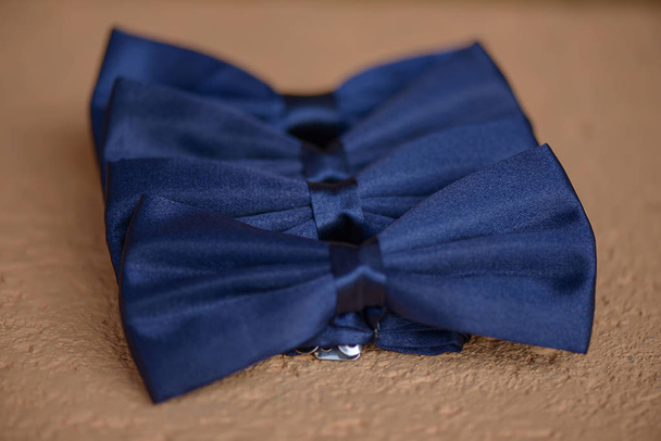 Cuatro lazos de lazo de seda azul alineados con enfoque selectivo posicionados en una superficie beige suave
 - Foto, Imagen