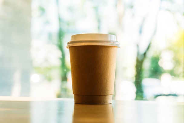 Горячий кофе латте в бумажной чашке на столе в кафе
 - Фото, изображение