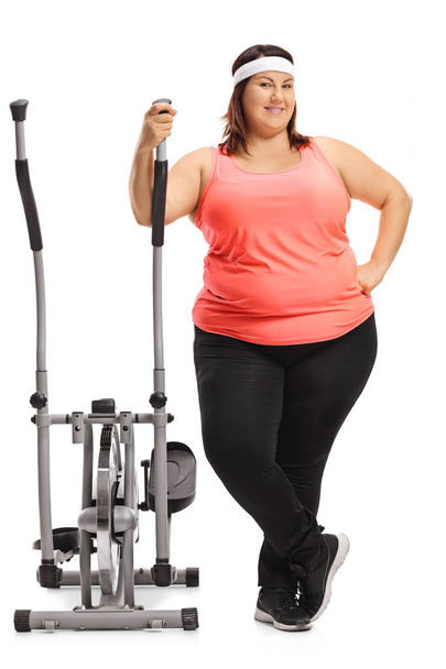 Overweight woman with a cross trainer machine - 写真・画像