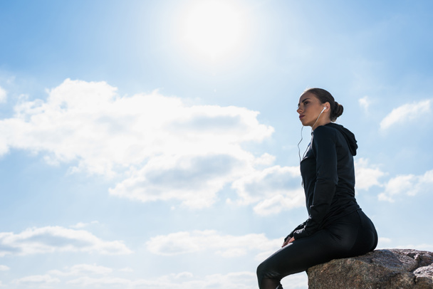 kayanın üzerinde oturan sportif kadın - Fotoğraf, Görsel