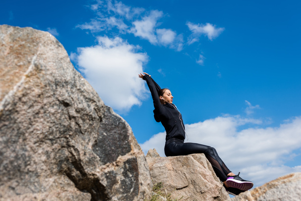 спортивна жінка сидить на каменях
 - Фото, зображення