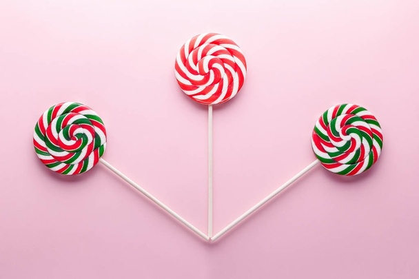 Three spiral lollipops on a stick on a pink background. Top view - Photo, Image