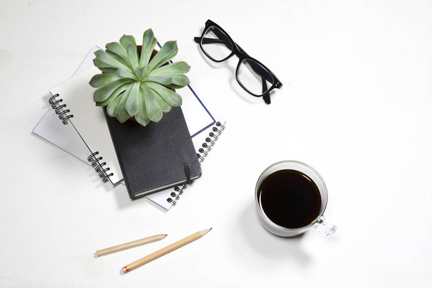 the Top view of white office desktop with plant, coffee cup, glasses and stationery items. Mock up - Zdjęcie, obraz