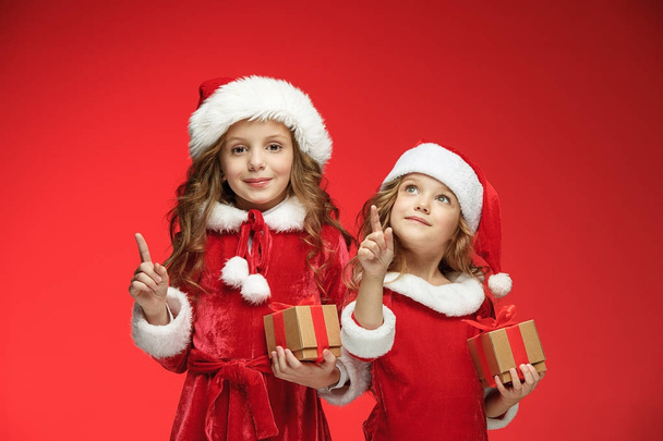 Two happy girls in santa claus hats with gift boxes - 写真・画像