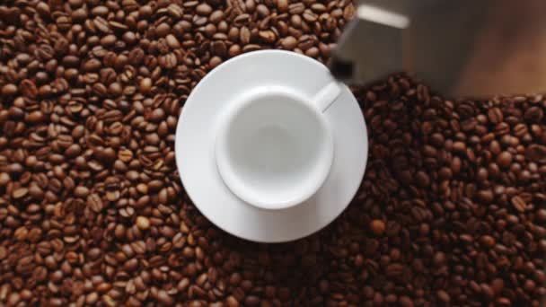 Verter una taza de café caliente y granos de café tostados
 - Imágenes, Vídeo