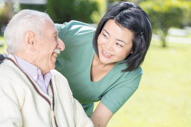 Active elderly retired man outdoor with asian nurse - Photo, Image