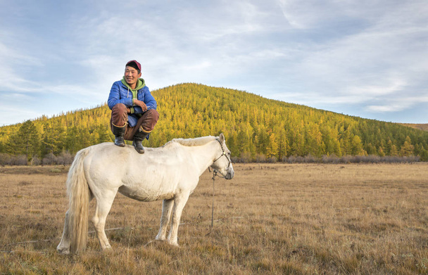 mngolian homem sentado em um cavalo branco
 - Foto, Imagem