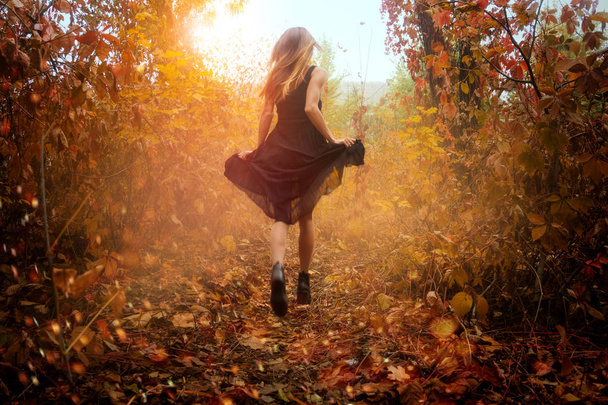 funny girl in black dress running in golden autum forest - Foto, Bild