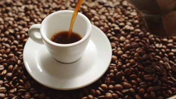 Verter una taza de café caliente y granos de café tostados
 - Imágenes, Vídeo