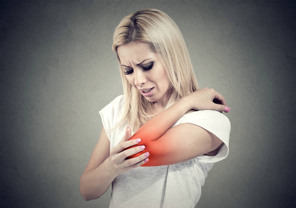 Sad woman with joint inflammation. Female's elbow. Arm pain and injury. - 写真・画像