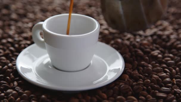 Ρίχνει φλιτζάνι ζεστό καφέ και καβουρδισμένους κόκκους καφέ - Πλάνα, βίντεο