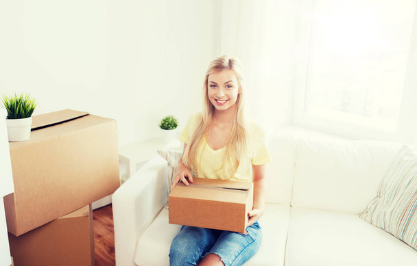 smiling young woman with cardboard box at home - Fotó, kép
