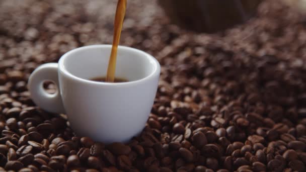 Wylewanie filiżankę gorącej kawy i palonych ziaren kawy - Materiał filmowy, wideo
