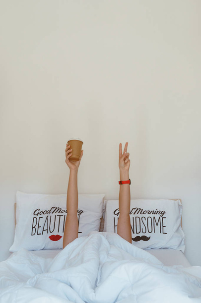 Mani della donna che mostrano il v-segno e tenendo tazza sotto coperta o
 - Foto, immagini