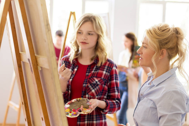 artists discussing painting on easel at art school - Φωτογραφία, εικόνα
