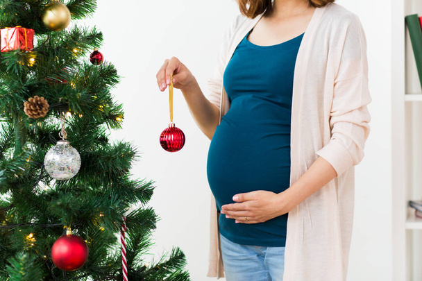 pregnant woman decorating christmas tree - Foto, afbeelding