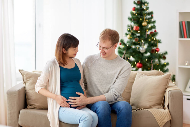 pregnant wife with husband at home at christmas - Фото, зображення