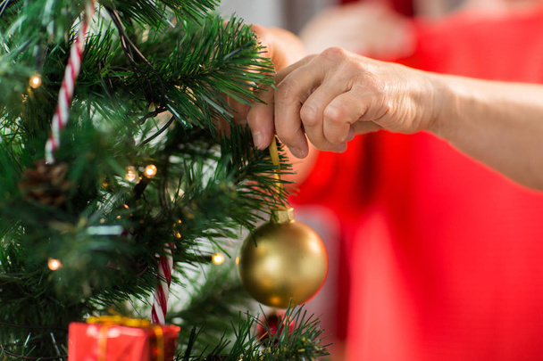 close up of senior woman decorating christmas tree - Foto, imagen