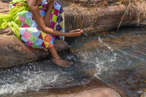 Frau in afrikanischem Outfit am Rande des fließenden Flusses. interaktin - Foto, Bild