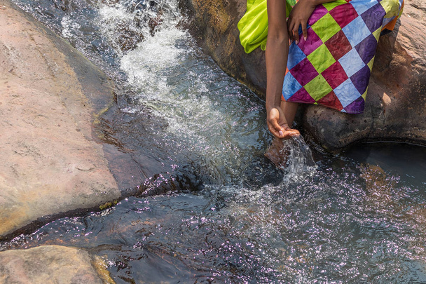 Frau in afrikanischem Outfit am Rande des fließenden Flusses. interaktin - Foto, Bild