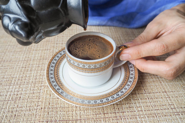  Uma mão a segurar um café. Café preto derramado dos turcos
. - Foto, Imagem