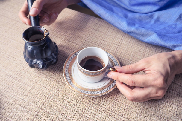  Mano sosteniendo una taza de café. Café negro vertido de los turcos
. - Foto, Imagen