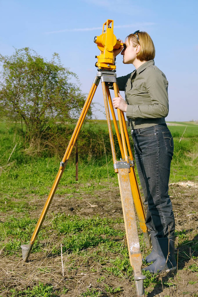 Geodeettista kartoitusta tekevä naisgeodeettinen tutkija
 - Valokuva, kuva