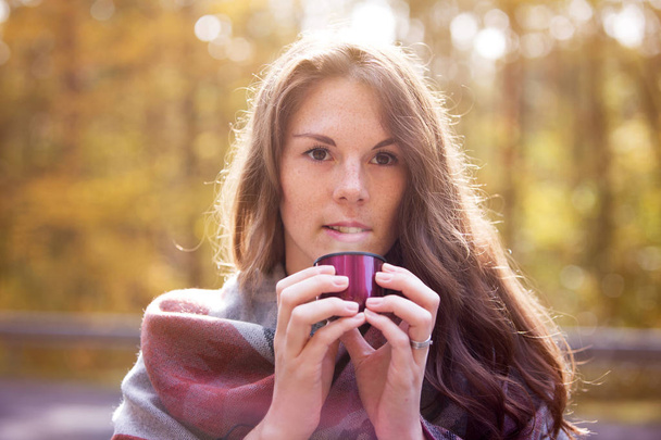 young woman outside drinking from cup in autumn - Foto, imagen