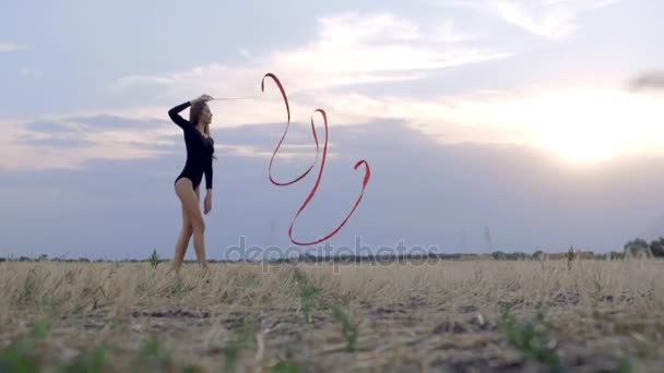 Jonge brunette vrouw dans ritmische gymnastiek, moderne met rood lint. - Video