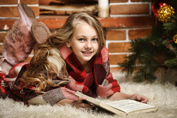 Girl reading a book by the fireplace - Foto, Bild