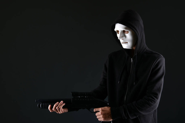 Маскований злочинець тримає пістолет
 - Фото, зображення