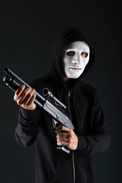 Masked criminal holding a gun - Фото, изображение