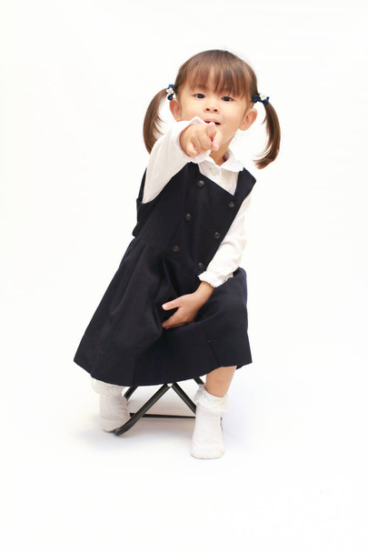 Японська дівчина на стілець, вказуючи на камеру в офіційну одяг (2 років) - Фото, зображення