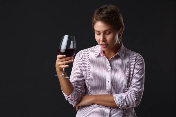 Beautiful girl with a glass of red wine on a black background. - Foto, imagen