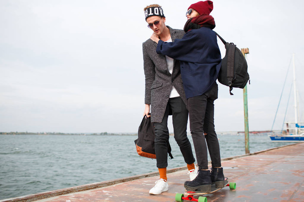 The guy with the girl on the pier the girl is riding on the skateboard - 写真・画像