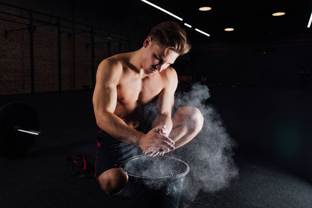 Fitness model trainer rubs his hands with chalk and talc so that fingers do not slip or slide. - Foto, Imagen