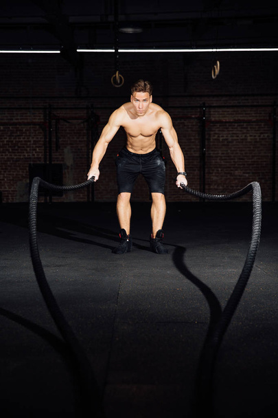Fitness man workout with battle ropes at gym. training exercise fitted body in club. Torso. - Foto, Imagem