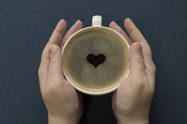 Coffee in a cup with a heart in hands - 写真・画像