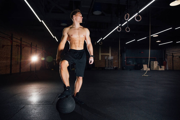 Confident muscled man doing push up from MEDICINE ball in gym. - Photo, Image